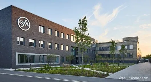 Verwaltungsgebäude aus dunklem Klinker mit GfA-Logo im Abendlicht