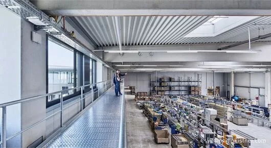Blick von oben in die Montagehalle mit Arbeitsplätzen und Regalen