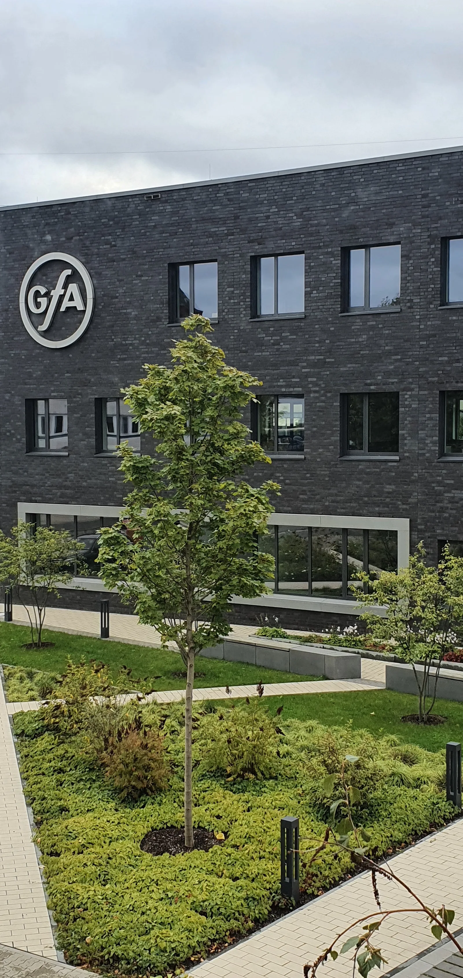 Fassade des Verwaltungsgebäudes mit GfA-Logo über einem bepflanzten Innenhof
