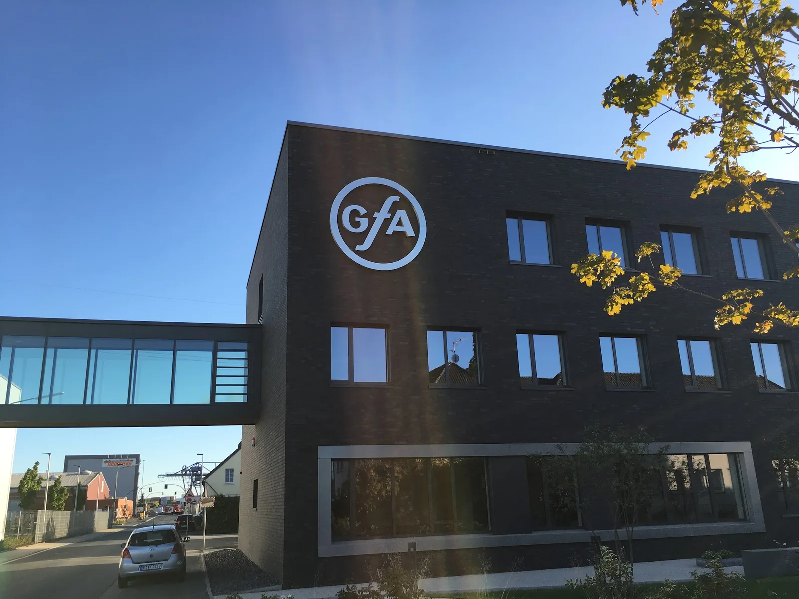 Gebäude mit GfA-Logo und gläserner Brücke im Gegenlicht