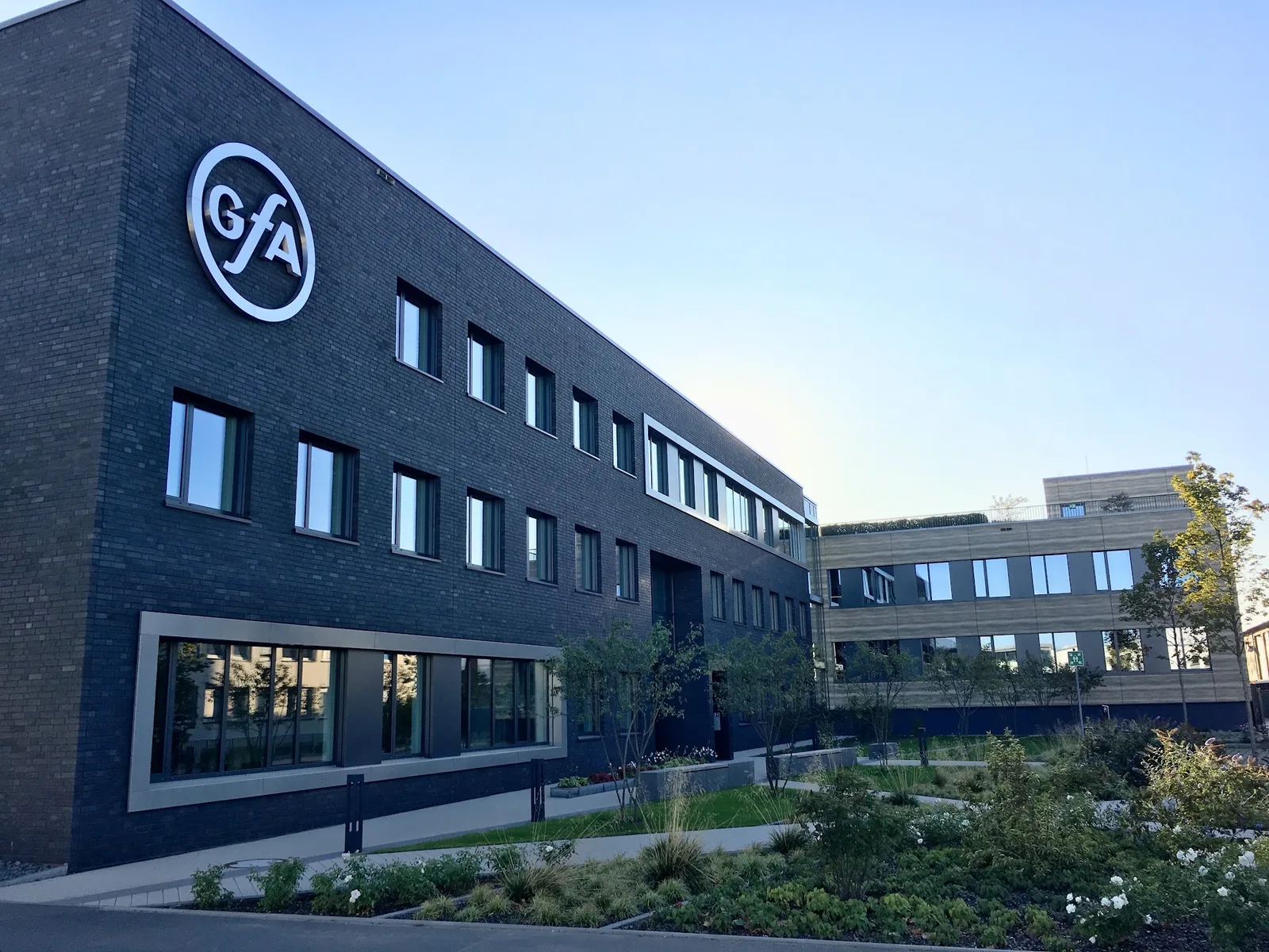 Verwaltungsgebäude der GfA an der Wiesenstraße in Düsseldorf, dunkler Klinker mit großem GfA-Logo, davor ein bepflanzter Garten